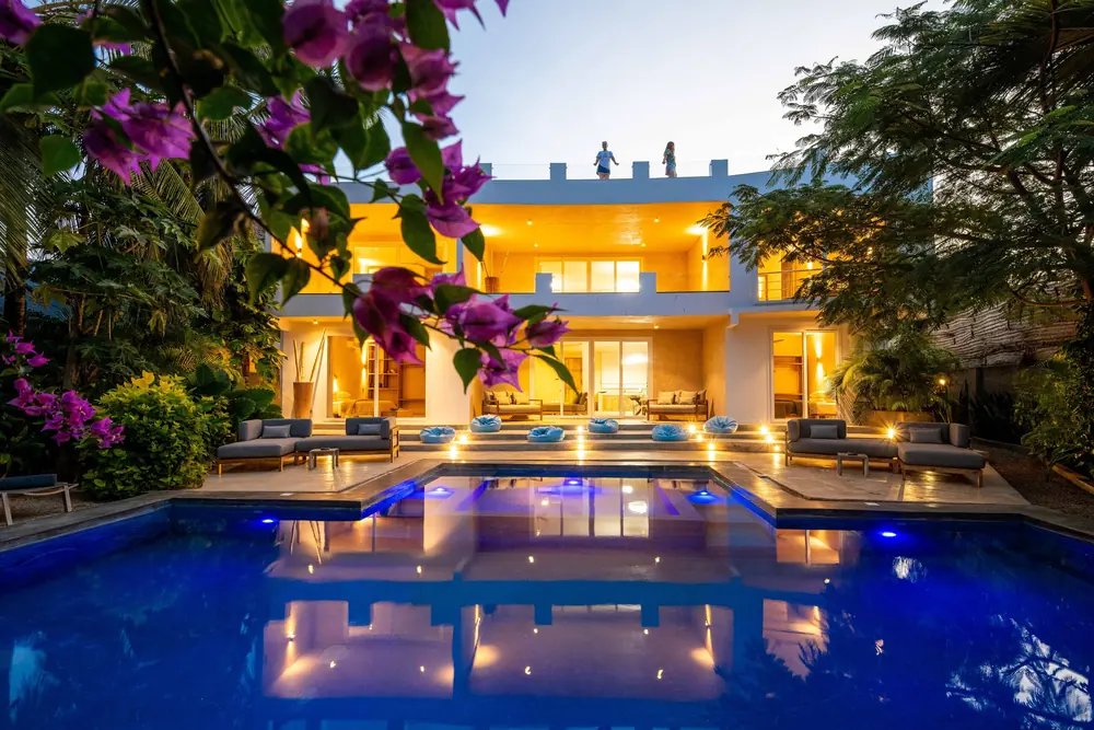 The villa lit up at dusk, reflected in the pool